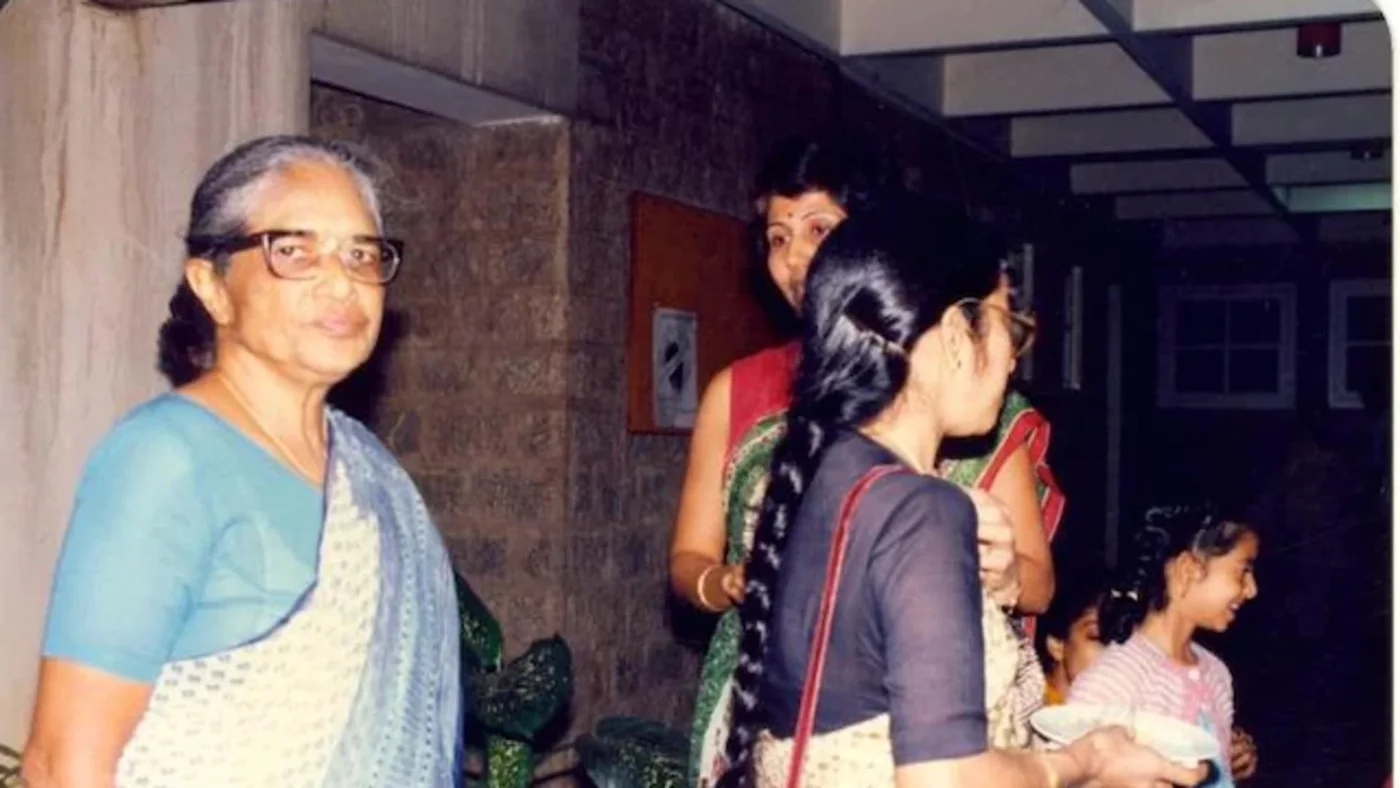 Anna Mani at left in glasses and a blue blouse, standing indoors with three companions in a colour photograph