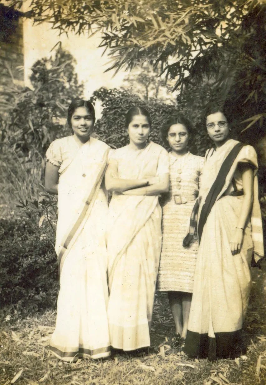 Anna Mani with three companions in saris and a dress, standing beneath bamboo, a group portrait from the family archive